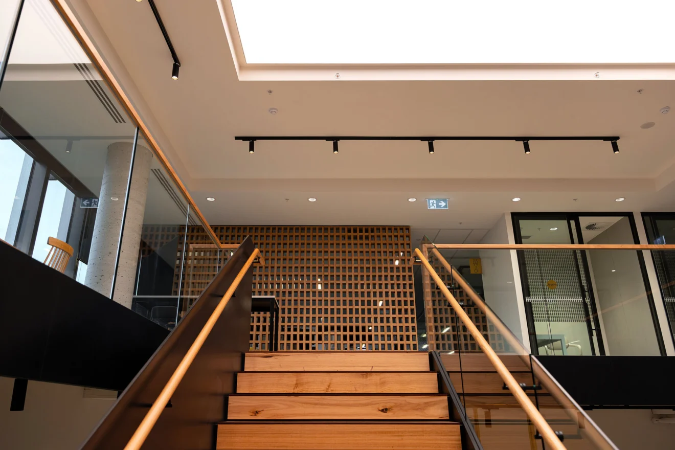Timber stair with track lighting between the two Acciona office levels