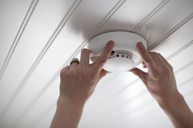 Smoke alarm being fitted to a ceiling